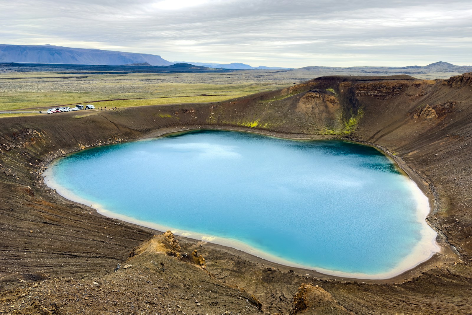 Lago azul intenso en el cráter volcánico de Krafla, Islandia, rodeado de un paisaje extraordinario.